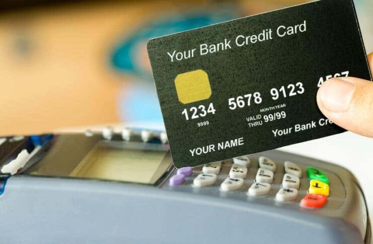 hand holding a credit card with credit card machine